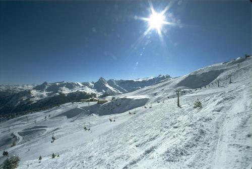 a snow covered ski slope with the sun in the sky at Haus zur Kapelle in Sankt Gallenkirch