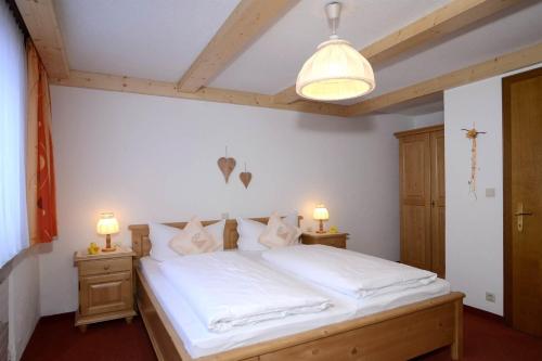 a bedroom with a bed with white sheets and two lamps at Haus Saler in Silbertal