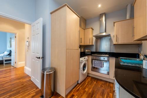 a kitchen with wooden cabinets and a washer and dryer at Camden Apartment A/Apartment in London