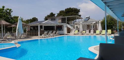 una gran piscina con sillas y sombrillas en Hotel Zafira en Skala Rachoniou