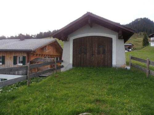 a small house with a wooden door in a field at Haus zur Kapelle in Sankt Gallenkirch