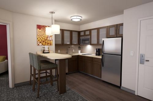 a kitchen with a table and a refrigerator at Staybridge Suites Charlottesville Airport, an IHG Hotel in Charlottesville