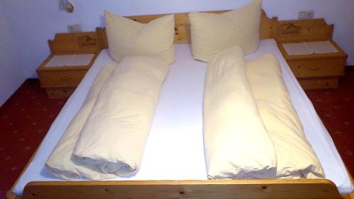 a bed with white sheets and pillows on it at Frühstückspension Gweil in Sankt Gallenkirch