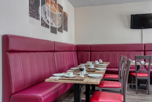 a red booth in a restaurant with a table and chairs at Centro Hotel Böblingen, Trademark Collection by Wyndham in Böblingen