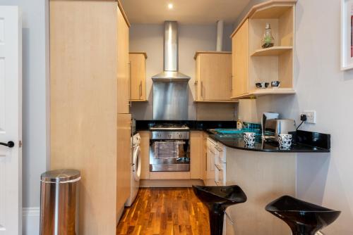 a kitchen with wooden cabinets and black counter tops at Camden Apartment A/Apartment in London