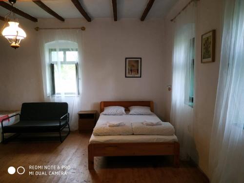 een slaapkamer met een bed, een stoel en een raam bij Darutollas Vendégház in Ópusztaszer