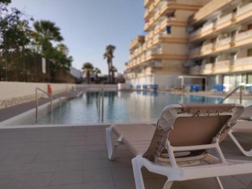 una silla sentada frente a una piscina en Apartamentos 2 Las Americas, en Playa de las Américas