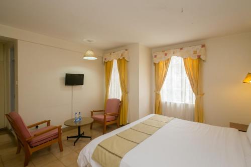 um quarto com uma cama, uma mesa e cadeiras em Corat Africa Hotel em Nairobi