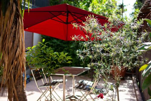 una sombrilla roja y sillas en un jardín en Callas Room Opera, en Catania