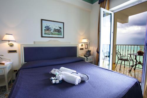 a bedroom with a bed with a purple bedspread at Lloyd's Baia Hotel in Vietri sul Mare