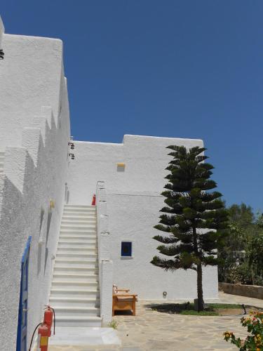 a white building with a staircase next to a tree at Agia Anna Living in Agia Anna Naxos
