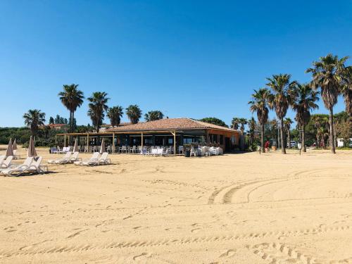 una playa con sillas y palmeras y un edificio en loumax, en Gassin