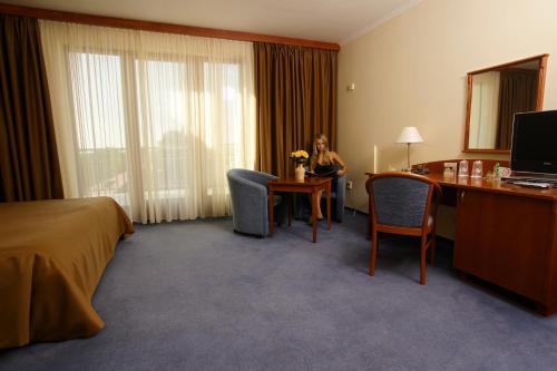 a woman sitting at a desk in a hotel room at April hotel Panorama in Rychnov nad Kněžnou