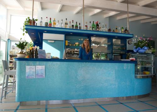 a woman standing behind a bar in a restaurant at Delle Rose Camping & Glamping Village in Isolabona