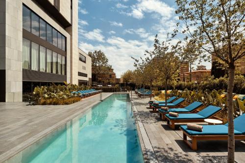 uma piscina com espreguiçadeiras ao lado de um edifício em Grand Hyatt Barcelona em Barcelona