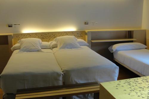 a bedroom with two beds with white sheets at Hotel Continental Balneario de Panticosa in Panticosa
