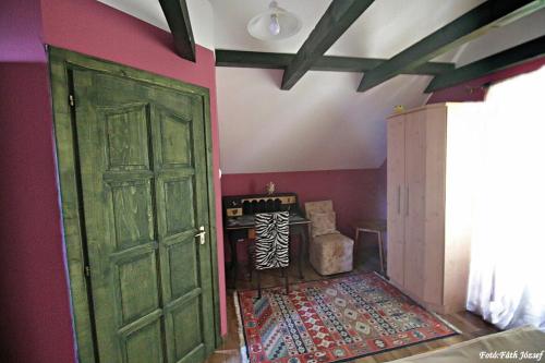a green door in a room with a rug at Két Kapu Udvarház in Szentlászló