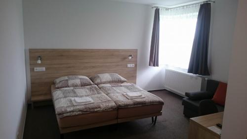 a bedroom with a bed and a chair and a window at Penzion Skalka in Skalka