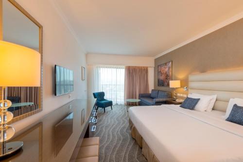 a hotel room with a large bed and a chair at Queen of Sheba Eilat in Eilat
