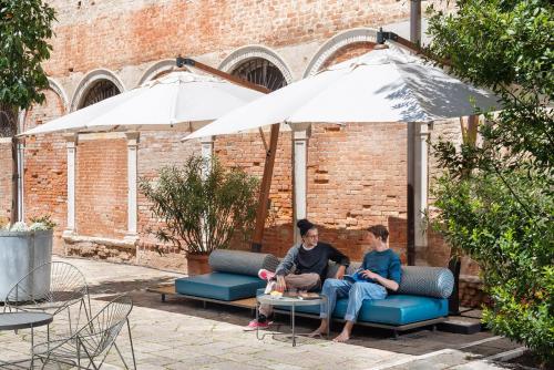 two people sitting on a couch under an umbrella at Combo Venezia in Venice