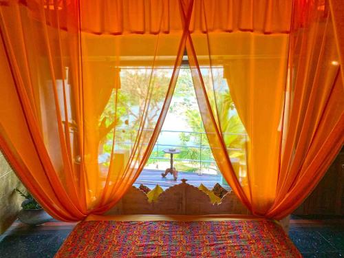 a bed with an orange curtain and a window at Aathma Colombo House in Colombo