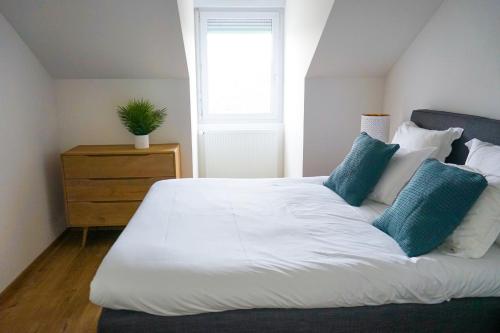 une chambre avec un grand lit blanc avec des oreillers bleus dans l'établissement L'Eden Urbain - 2 Chambres, à Brive-la-Gaillarde