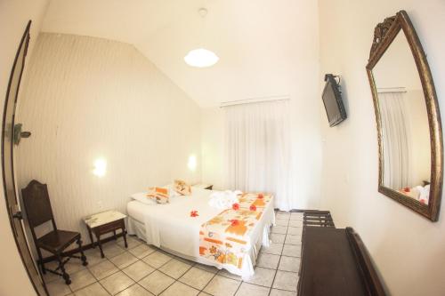 1 dormitorio con cama y espejo en Pousada do Galo, en Porto de Galinhas