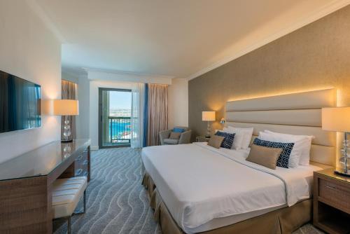 a hotel room with a large bed and a television at Queen of Sheba Eilat in Eilat