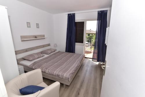 sypialnia z łóżkiem, krzesłem i oknem w obiekcie Apartment Hemingway w mieście Malinska