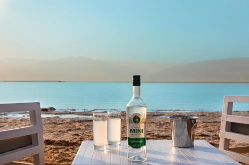 a bottle of wine sitting on a table on the beach at Herbert Samuel Milos Dead Sea in Ein Bokek