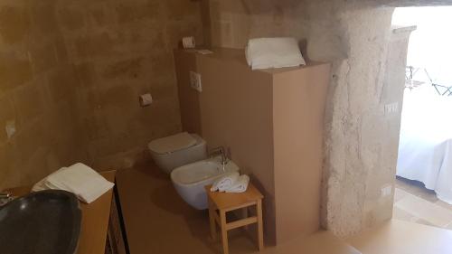 a bathroom with a toilet and a sink and a stool at 5 Elementi Sassi Matera in Matera