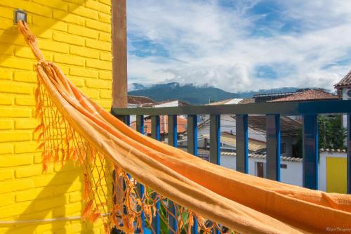 a hammock hanging on the side of a yellow building at Pousada Talismã in Paraty