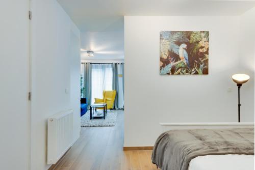 Dormitorio blanco con cama y silla amarilla en Royal Arts-Loi Studio, en Bruselas