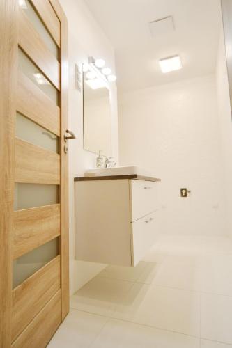 a bathroom with a sink and a wooden door at Moment Apartments in Szolnok