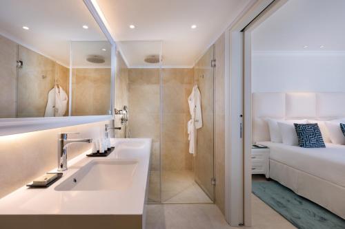 a bathroom with a sink and a shower and a bed at Herbert Samuel Milos Dead Sea in Ein Bokek