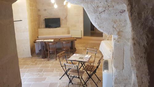 a room with a table and chairs and a television at 5 Elementi Sassi Matera in Matera