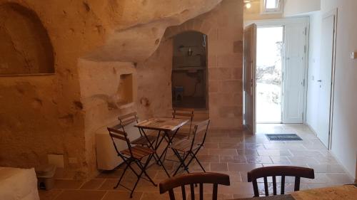 a room with a table and chairs in a stone wall at 5 Elementi Sassi Matera in Matera