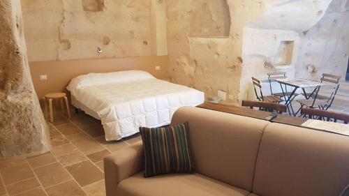 a bedroom with a bed and a table and a couch at 5 Elementi Sassi Matera in Matera