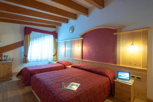 a bedroom with two beds and a laptop on a table at Hotel Angelo in Passo del Tonale