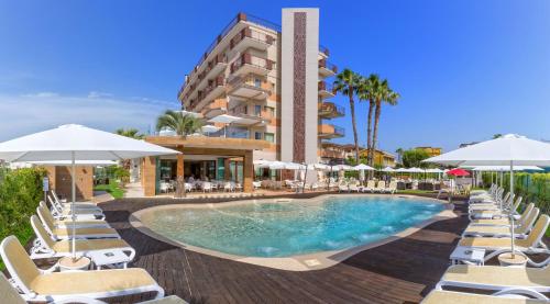 uma piscina com cadeiras e guarda-sóis em frente a um hotel em Almaluna Hotel & Resort em Alba Adriatica