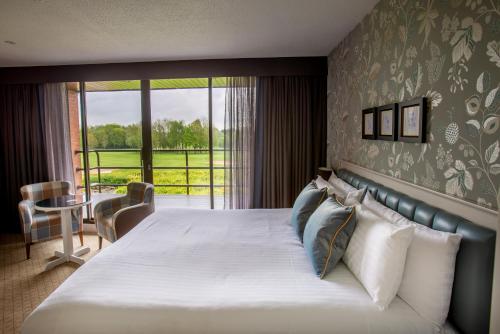 a bedroom with a large bed with a large window at Abbey Hotel Golf & Spa in Redditch