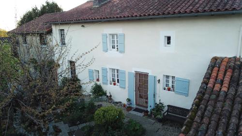 a white house with blue windows and a roof at La Maison Des Fleurs in Montembœuf