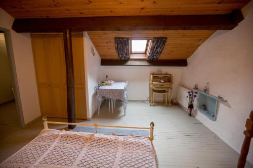 an attic room with a bed and a table at La Maison Des Fleurs in Montembœuf