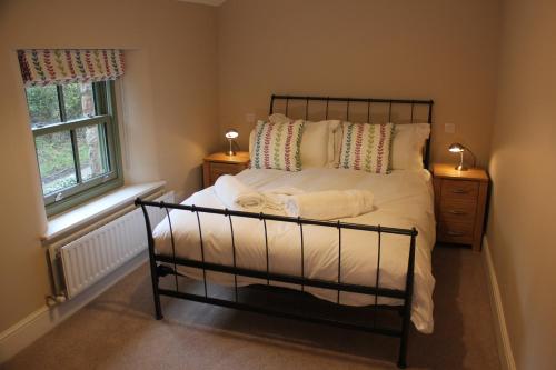 a bedroom with a bed with white sheets and a window at Rose Cottage in Sandford