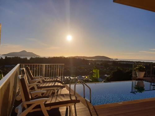 a balcony with chairs and a swimming pool with the sunset at The Ridge Residence in Victoria
