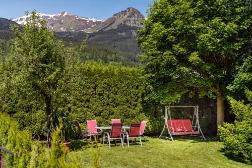 three chairs and a table in a yard with mountains at Hotel Alpenhof - New Sauna Area in Bad Hofgastein