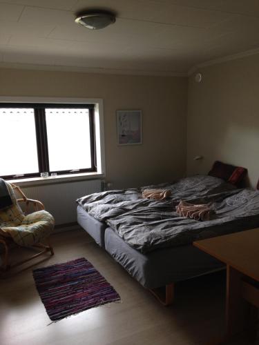 a bedroom with a bed and a chair and windows at Bramming city privat overnatning , ingen morgenmad in Bramming
