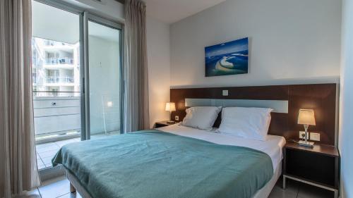 - une chambre avec un lit et une grande fenêtre dans l'établissement Vacancéole - Résidence Le Crystal, à Cagnes-sur-Mer