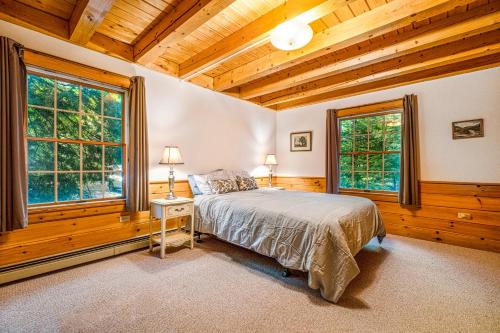 1 dormitorio con 1 cama y 2 ventanas en The Cabin on Squam Lake, en Center Harbor