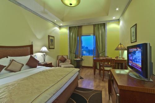 a hotel room with a bed and a television at Hotel Hindusthan International, Kolkata in Kolkata